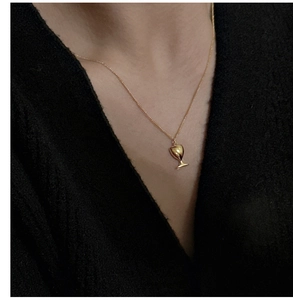 Détail macro d'un collier pendentif verre à vin doré sur un mannequin en tricot noir