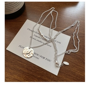 Detail of S925 silver double-layered necklace with a hammered coin pendant and wave bar