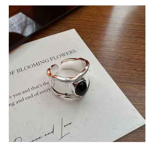 Macro shot of silver wide band ring with black agate stone and wavy texture on surface