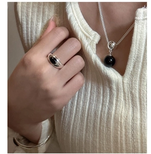 Close-up of S925 silver ring with black onyx stone paired with jewelry on casual knitwear