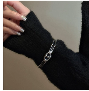 Détail du bracelet en argent S925 avec émail noir sur une manche de pull en tricot