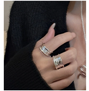 Detailed view of silver minimalist wavy ring and necklace on model with black outfit