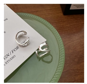 Macro detail of silver double-layered wavy cuff earrings on a glass decorative plate