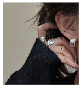 Macro detail of S925 sterling silver wavy rings and matching stud earrings on model