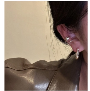 Close-up of a double-layered silver ear cuff with braided texture worn on a model's ear