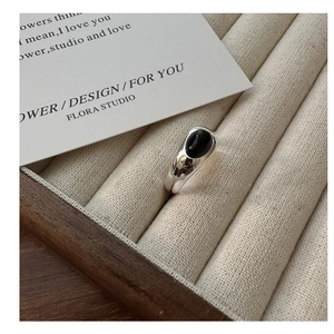 Detailed view of an S925 sterling silver ring with oval black onyx on a beige tray