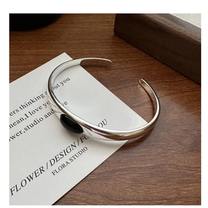Detail of S925 sterling silver open bangle with large oval black onyx on wooden background