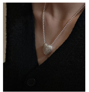 Detail of S925 sterling silver heart necklace with hammered texture on black knitwear