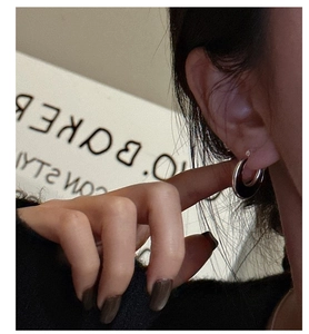 Close-up of a silver hoop earring with black enamel inlay worn by a model in a trendy style