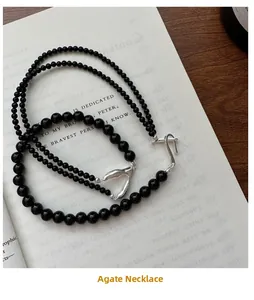 Detailed view of dual agate bead necklaces with silver fishtail clasp on a vintage book