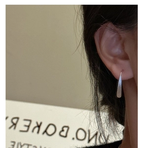 Macro shot of minimalist S925 sterling silver long teardrop earrings with brushed finish