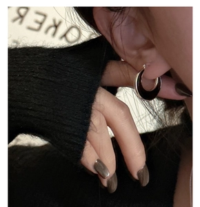 Close-up of crescent silver earrings with black enamel on a model's ear