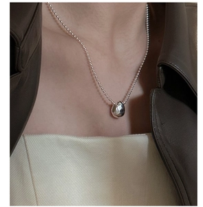 Macro detail of S925 sterling silver ball chain necklace with hammered water drop pendant