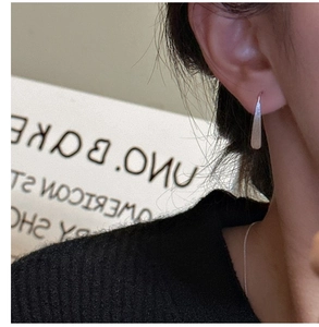 Detailed close-up of matte silver teardrop earrings on model with a minimalist design