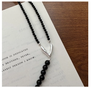 Detailed macro view of S925 silver Y-shaped necklace with black beads and polished metal parts