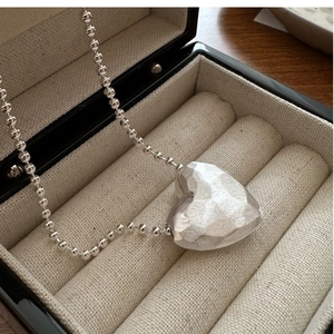 Detail of S925 sterling silver heart pendant necklace with hammered matte finish texture