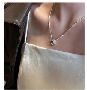Detail of S925 sterling silver teardrop necklace on a model with polished mirror finish