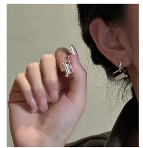 Macro detail of S925 sterling silver earrings with cylindrical texture and minimalist design