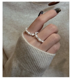 Close-up of handmade S925 silver ring with irregular white pearls on a knit background
