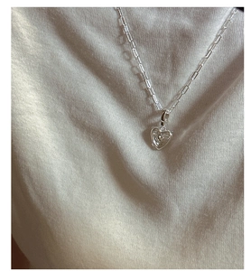 Détail d'un pendentif cœur en argent S925 sur un collier chaîne trombone moderne