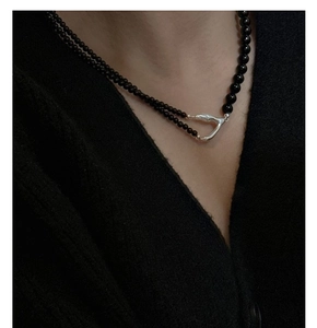 Detail of s925 silver Y-shaped necklace with black beads on black knitwear