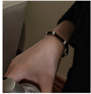 Close-up of S925 sterling silver beads on hand-woven brown cord bracelet worn on wrist