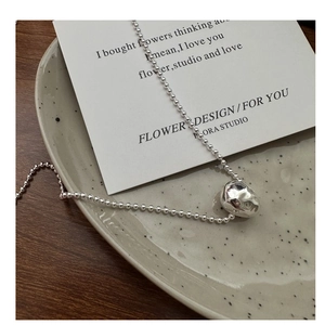 Macro detail of S925 sterling silver hammered teardrop pendant on bead chain necklace