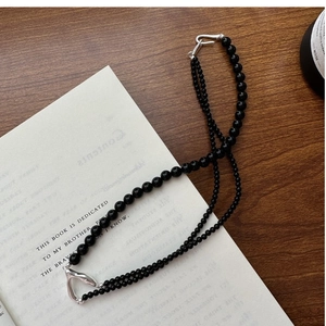 Detail view of double-layer black beaded necklace with silver clasp on a book surface