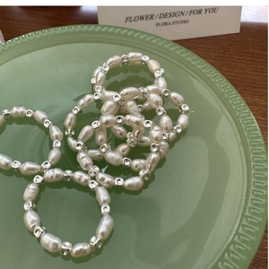 Detailed shot of baroque pearl elastic ring with silver square beads on green ceramic tray