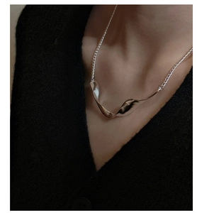 Detailed view of S925 sterling silver twisted wave necklace on a model with black clothing