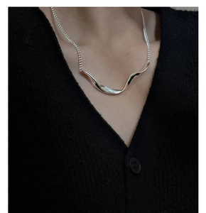 Close-up of S925 sterling silver wavy pendant necklace worn on a black knit top