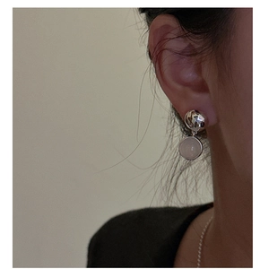 Gros plan de boucles d'oreilles en argent S925 avec sphères texturées et perles d'agate blanche
