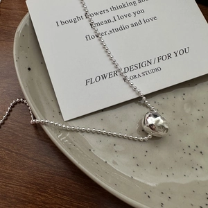 Minimalist S925 sterling silver ball necklace with textured lava pendant on ceramic tray
