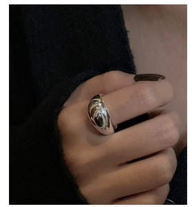 Macro shot of polished S925 sterling silver dome ring worn by a model on a dark backdrop