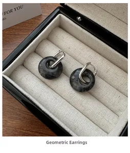 Close-up of geometric S925 sterling silver earrings with natural stone in a jewelry box