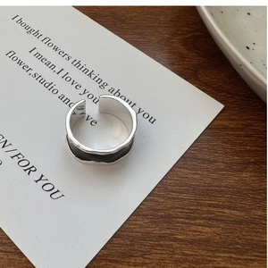 Detail of S925 sterling silver ring with irregular wave edges and black glaze finish
