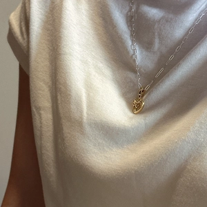 Collier minimaliste en argent S925 avec pendentif cœur doré porté sur un t-shirt blanc
