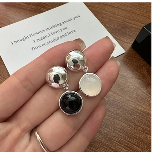 Détail de boucles d'oreilles en argent S925 avec agate noire et blanche en main