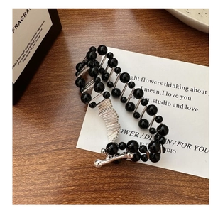 Macro shot of minimalist S925 silver beaded bracelet with black onyx charms on white card