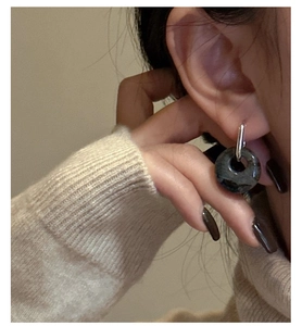 Detail of S925 sterling silver earring featuring a dark natural stone hoop on a model