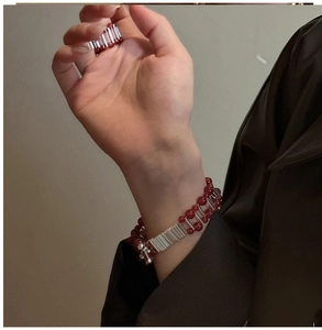 Detail of red agate beaded bracelet with silver metallic bars worn on a model wrist