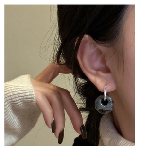 Detail of silver drop earrings with natural marble stone on a model wearing knitwear