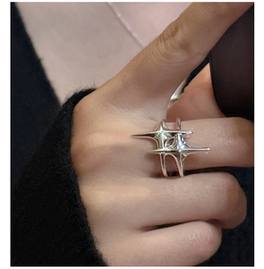 Détail macro d'une bague étoile en argent S925 portée sur un fond en maille noire