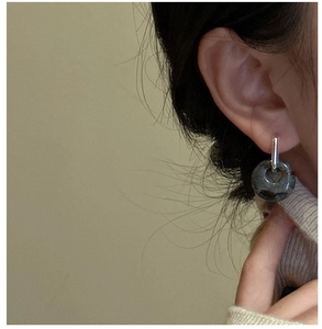 Detail of silver rectangular earring with a dark marble stone ring on model ear