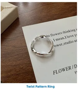 Close-up of a silver twisted wave texture ring on a minimalist art card display