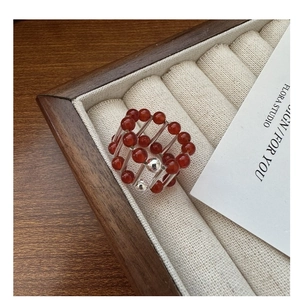 Macro view of a 3D red agate bead ring with silver frame in a wooden jewelry display