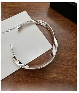 Gros plan du bracelet torsadé en argent massif S925 sur une table en bois rustique
