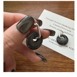 Macro shot of silver ear hoop with dark marble stone texture and rectangular metal clasp