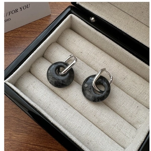 Close-up of S925 sterling silver earrings with grey natural stone in a jewelry box