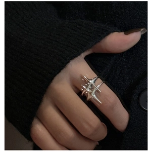 Détail d'une bague à pointes argentée portée par un mannequin en tricot noir pour un look punk Y2K